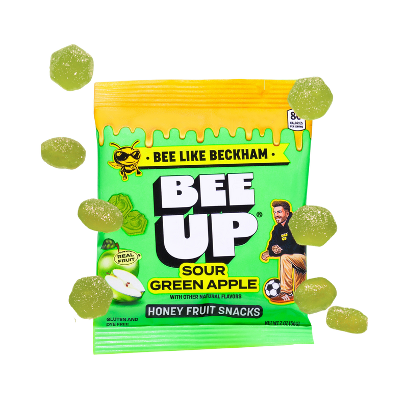 Packaging of Bee Up Sour Green apple with green and yellow design, surrounded by scattered gummy candies.